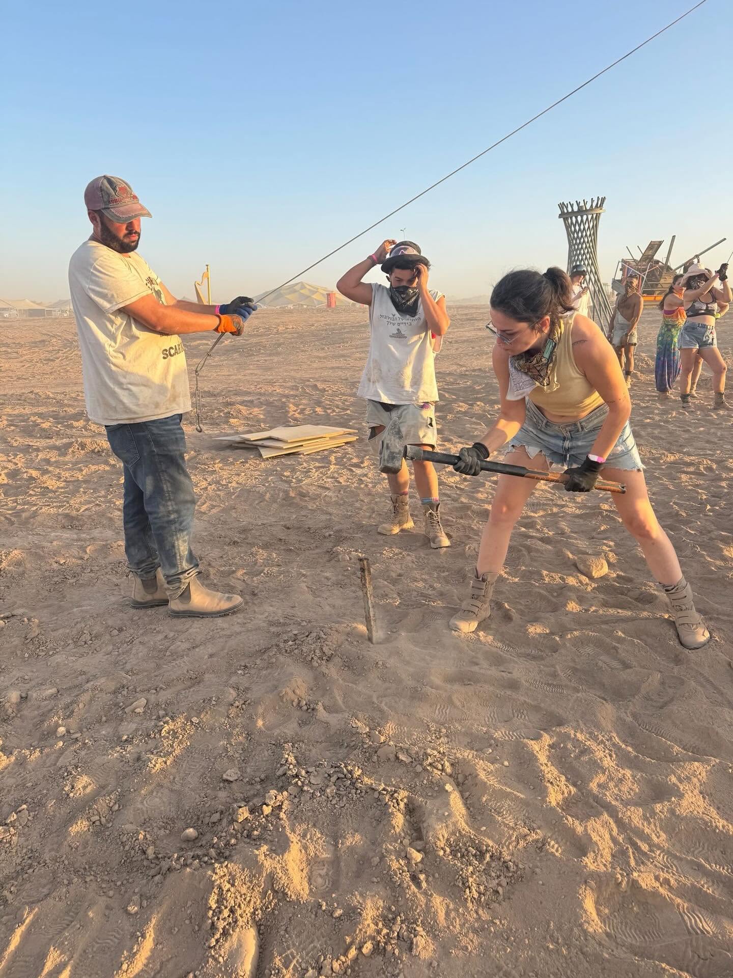 Driving stakes and tensioning a line on the playa during the build